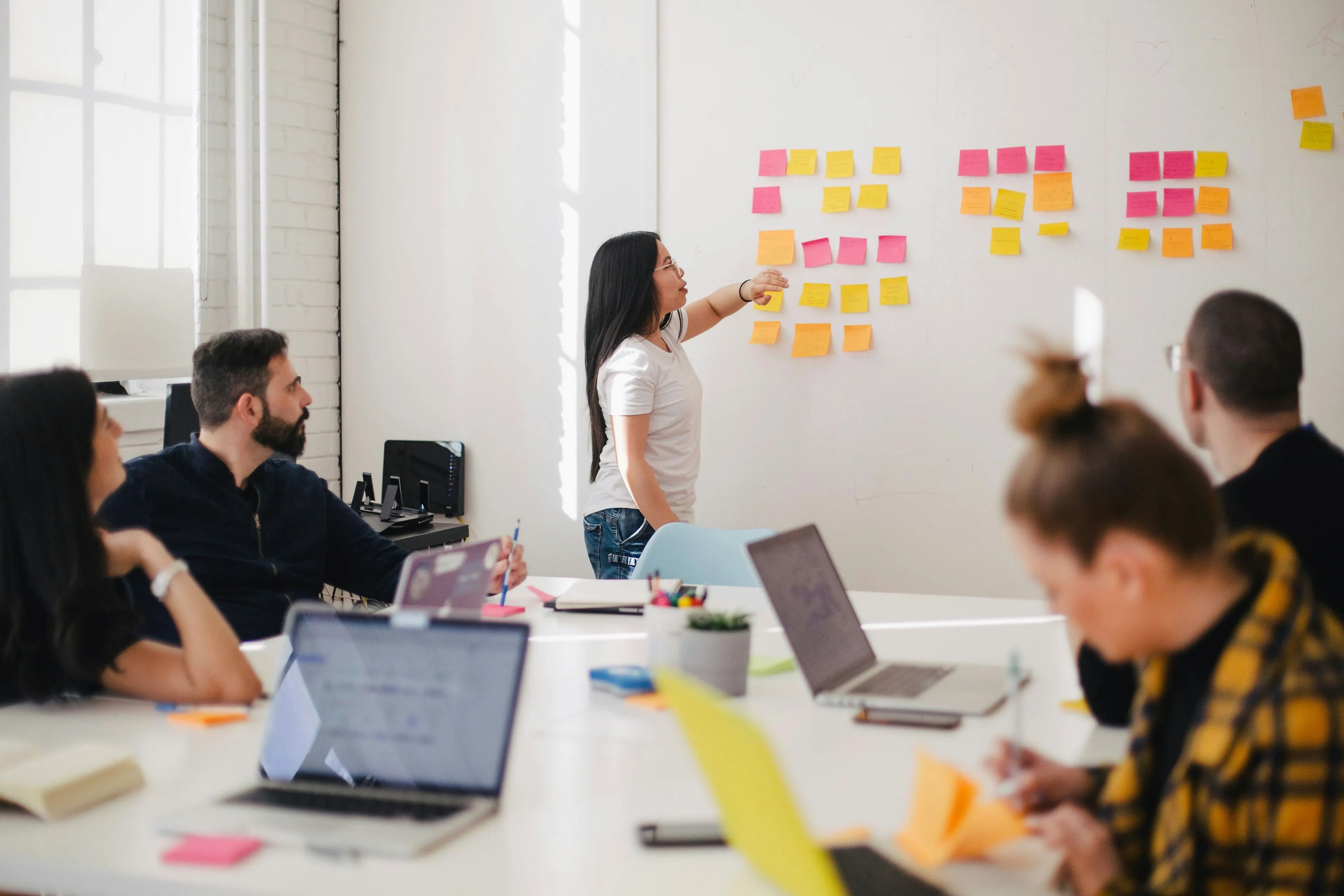 Une formatrice anime un atelier devant un mur de post-it